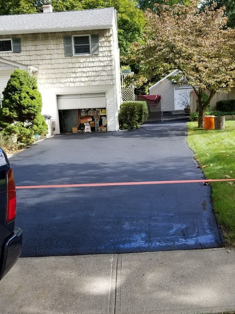Fully paved driveway with orange stripe across in front of a tan colored home.